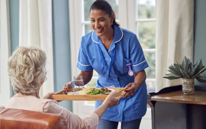 A woman serving food to an older person.