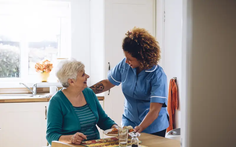 A nurse is helping an elderly woman with her food.