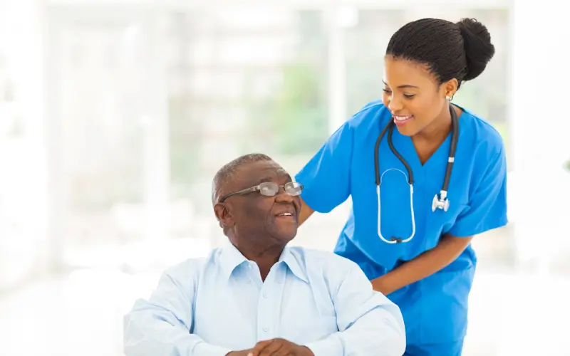 A nurse is helping an elderly man to sit down.