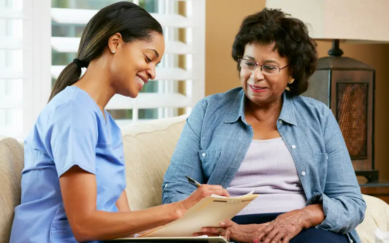 A woman and her nurse are smiling at each other.