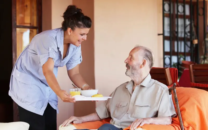 A woman serving food to an elderly man.