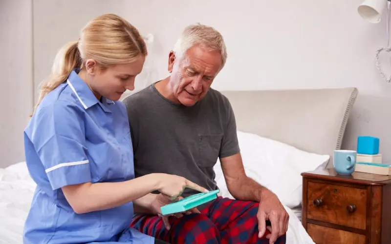 A nurse showing an elderly man something on his tablet.